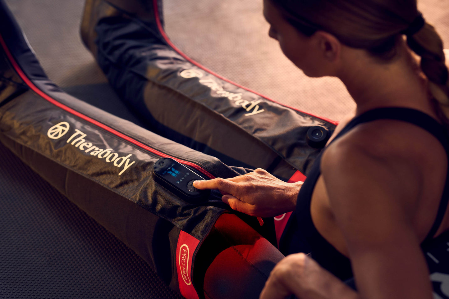 Female athlete using Recovery Boots with compression massage technology  from Therabody in a gym