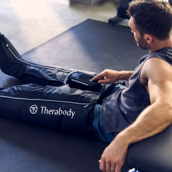 Man using Jetboots Recovery boots with pneumatic compression therapy in a gym